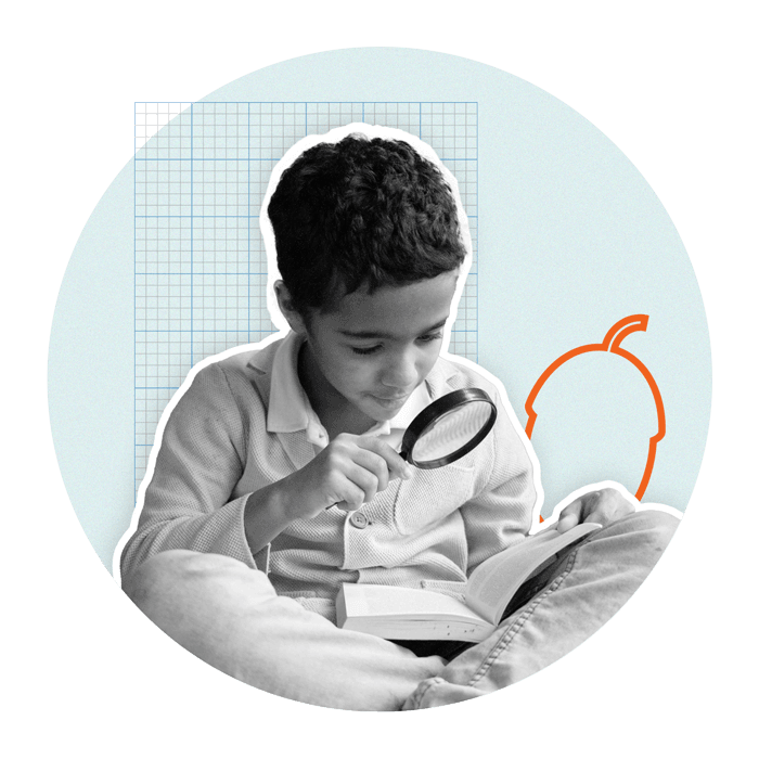 Boy reading a book through a magnifying glass