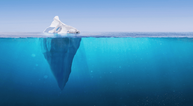 Iceberg floating in calm water, with a small peak above the water and a much larger mass underwater.
