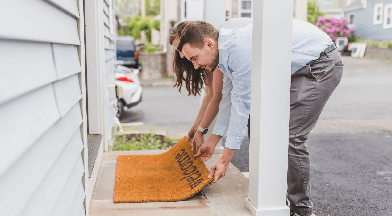Man and woman laying out a welcome mat outside the front door of their home