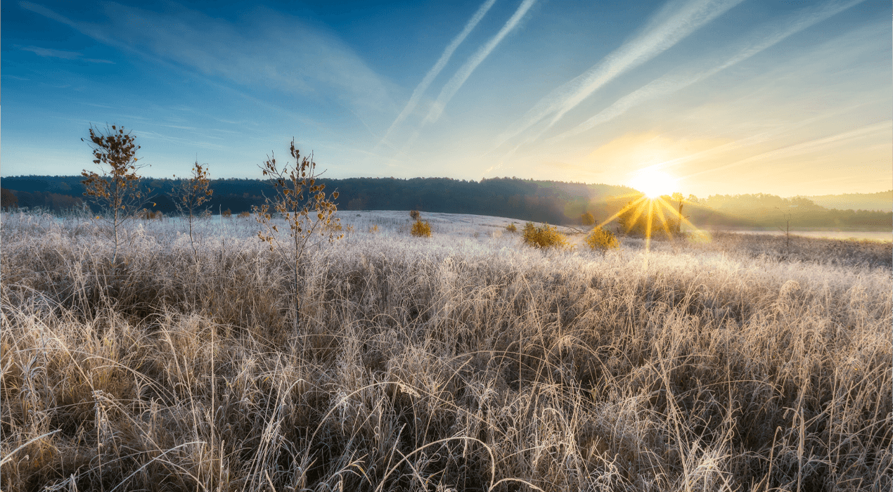 Sunrise over frosty fields, with hills in the background