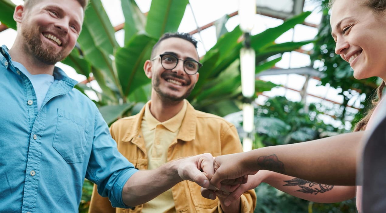 Group of three young people smiling and fist bumping each other