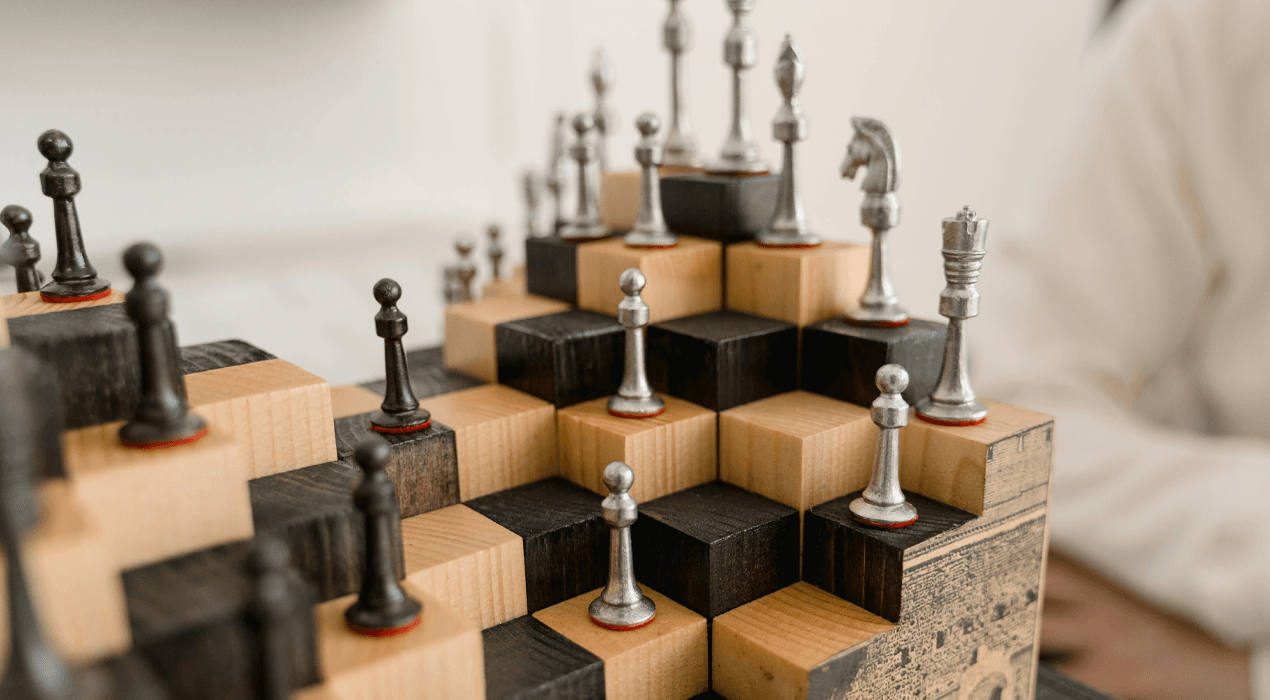 Chess pieces sitting on top of a series of layered black and brown boxes
