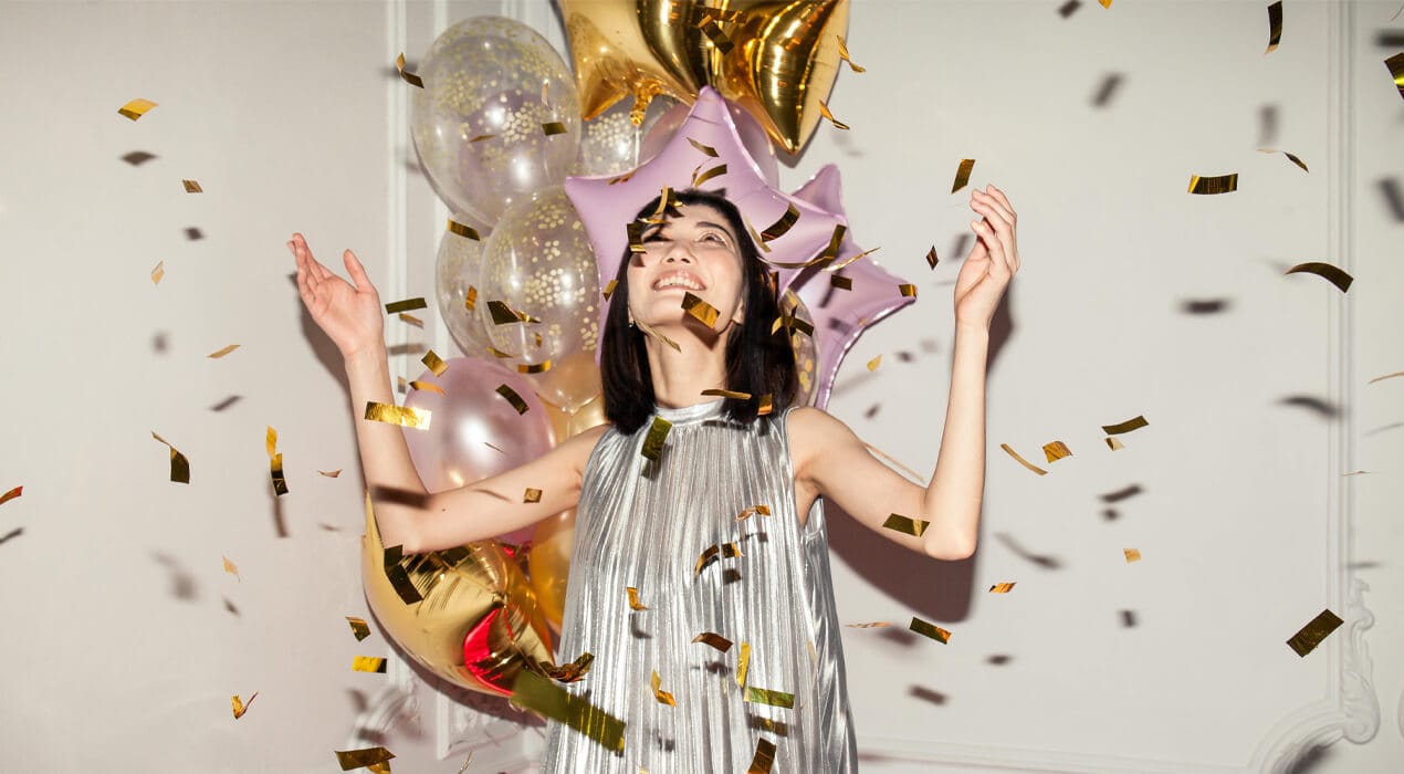 Woman excitedly looking up at falling confetti at a party