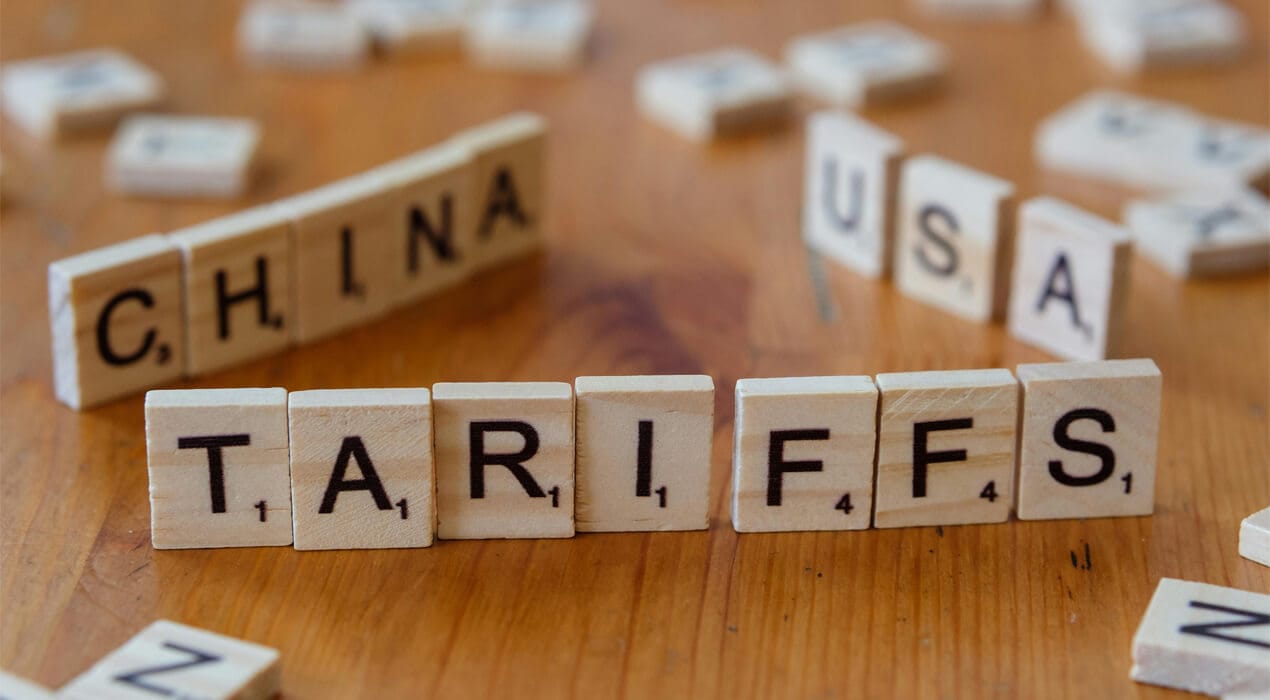 Scrabble pieces lined up on a table spelling out "tariffs", "China" and "USA"
