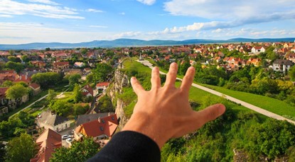 Hand in foreground, reaching out to houses in background