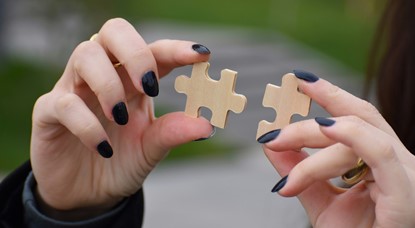 Young woman holding two jigsaw pieces that fit together