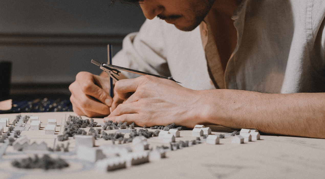 Man sitting at a table working on small model houses